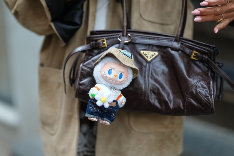 A Labubu plush toy attached to a brown Prada handbag.