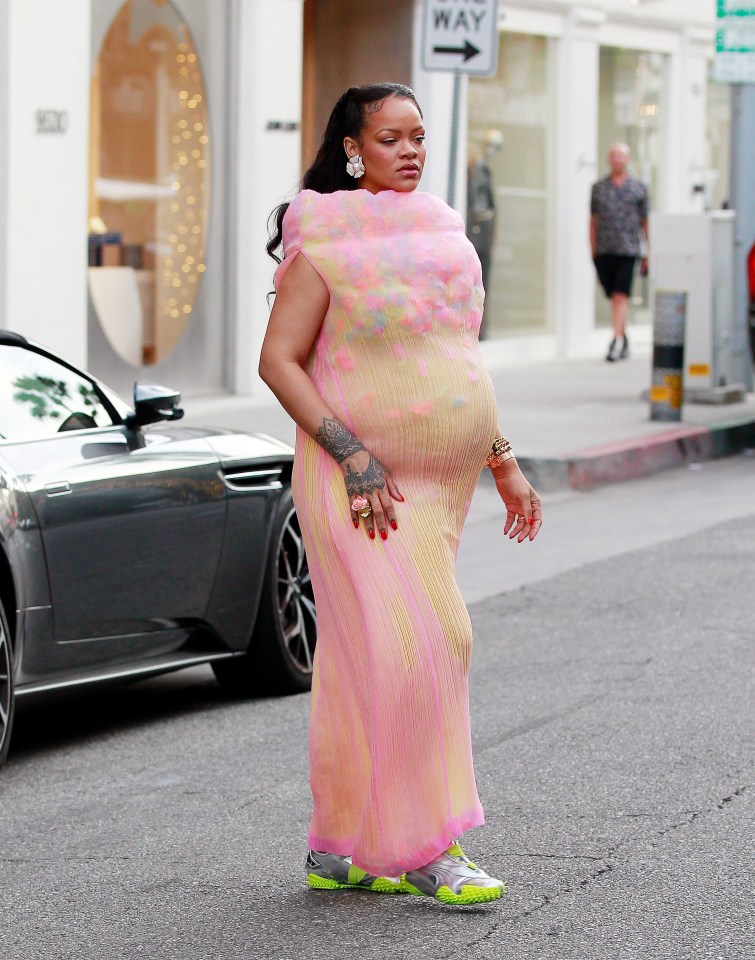 Rihanna walking down a street in Los Angeles, wearing a pink dress and Puma sneakers.