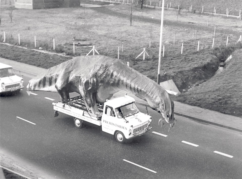 A large dinosaur model on a flatbed truck.