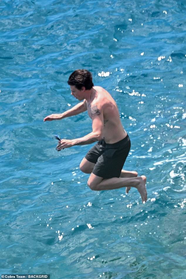 Meanwhile, the musician went shirtless, flashing his tattoos in black swimming shorts