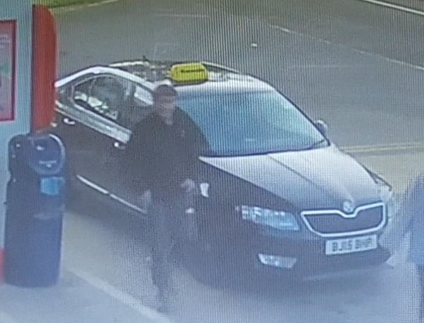 Security camera image of a man near a black Skoda Octavia.