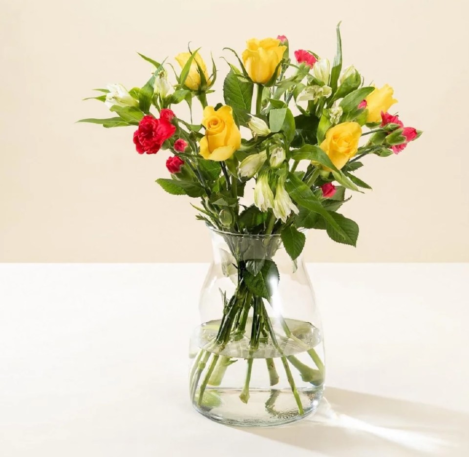 Bouquet of yellow roses and red carnations in a glass vase.