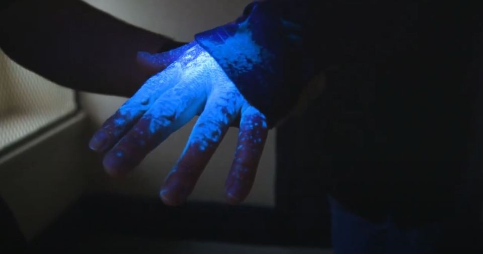 Hand coated in SelectaDNA tagging spray, glowing under UV light.