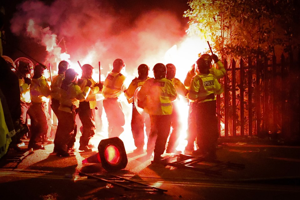 Police clashing with Legia Warszawa fans amidst flares.