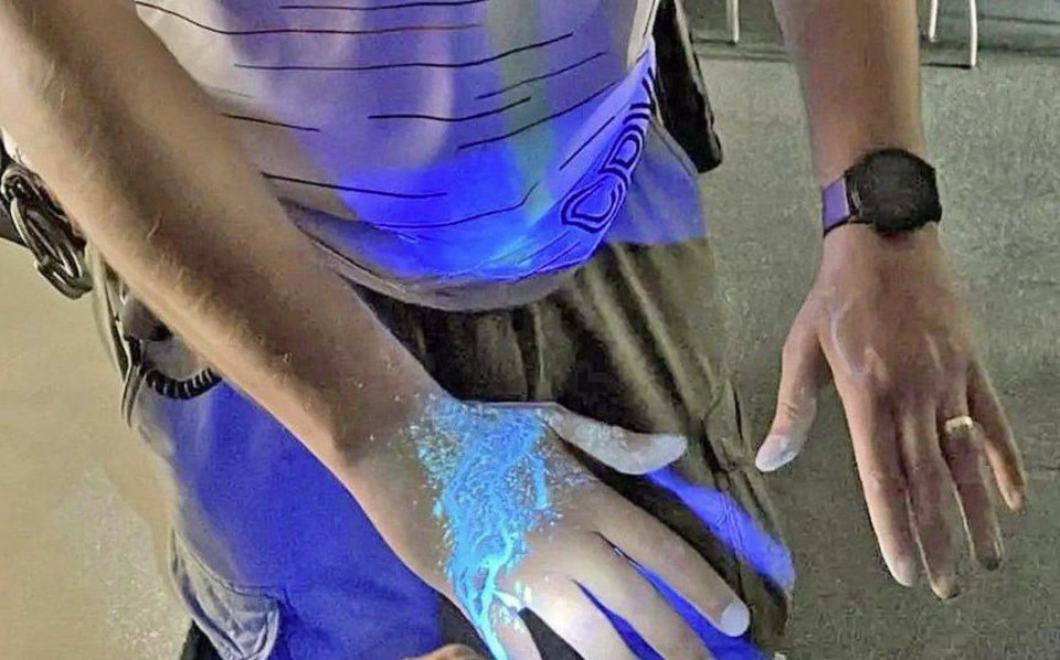 DNA tagging spray applied to a hand, glowing under UV light.