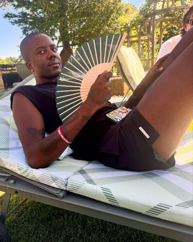 Man relaxing outdoors with a hand fan.