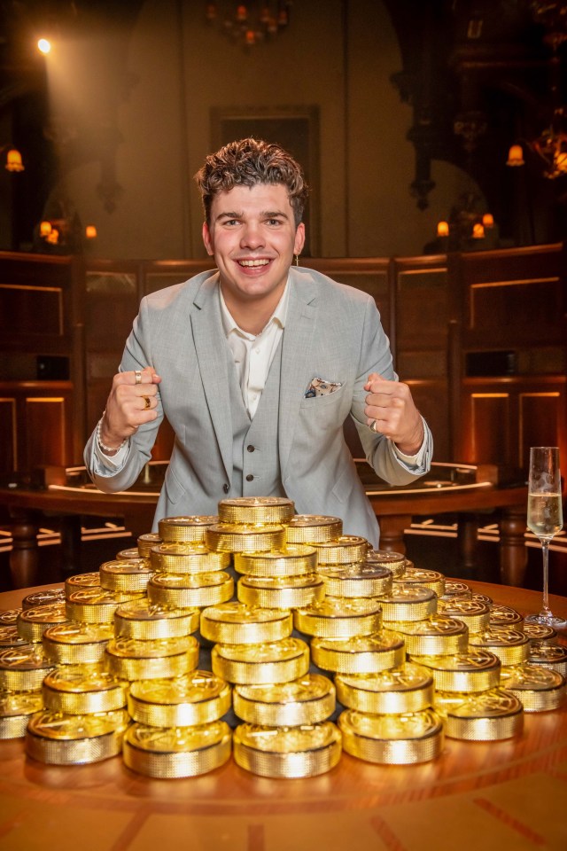 A man in a suit celebrates with a large pile of gold coins.