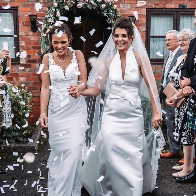 Two brides walking down the aisle, showered with confetti.