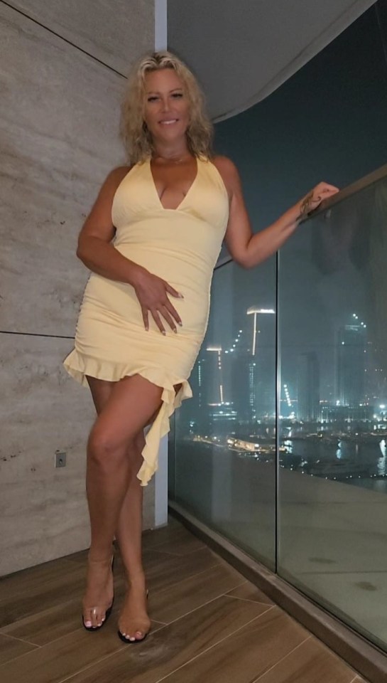 Woman in a yellow dress on a balcony at night.