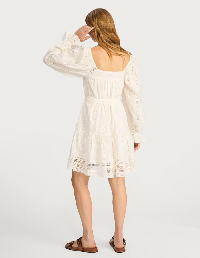 Ivory eyelet mini dress with puff sleeves and tiered skirt.