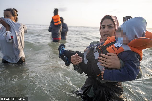 Migrants waded into the surf at Gravelines beach, between Calais and Dunkirk, yesterday - including some with children in their arms - as Labour's new scheme came into force