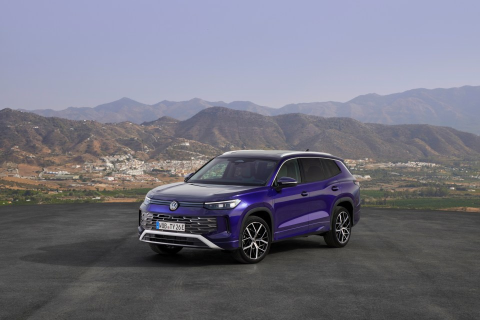 Purple Volkswagen Tayron SUV in front of mountains.