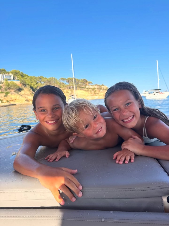 Three children smiling on a boat.