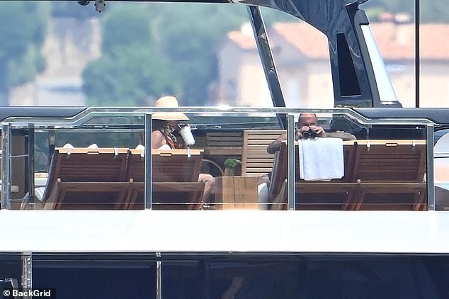 Victoria was sipping from a large cup while David looked out to sea