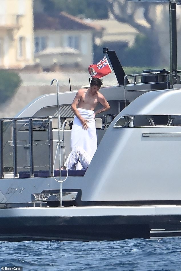 He wrapped up in a towel after following his dad in enjoying a cooling dip