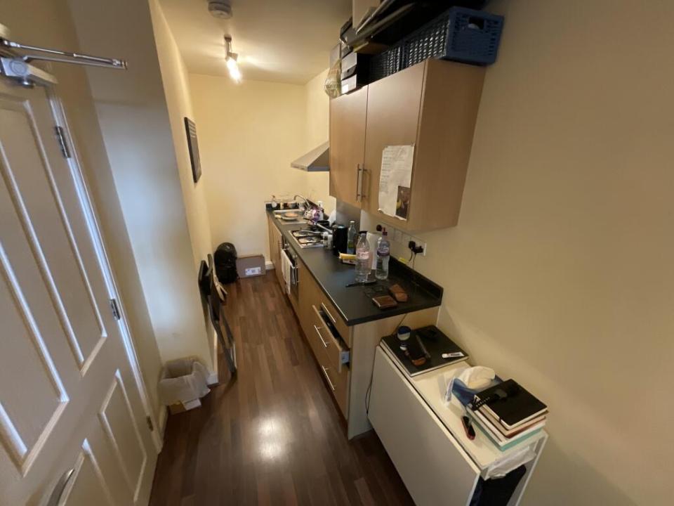 Interior view of a narrow studio apartment with a kitchen and living area.