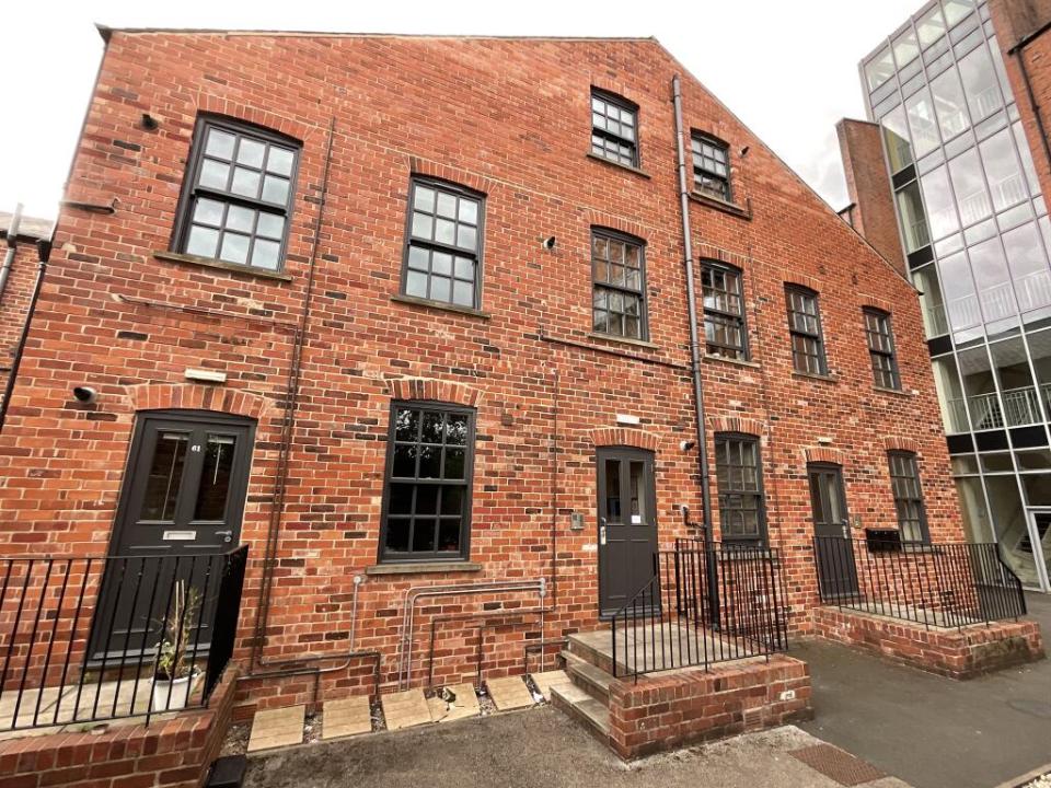 Exterior of a narrow brick building with multiple entrances.