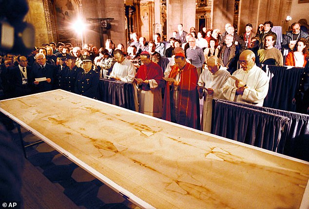 The shroud first appeared in 1354 in France. After initially denouncing it as a fake, the Catholic church has now embraced the shroud as genuine. Pictured, the burial cloth was on display in 1998 in the Cathedral of Turin for the first time in 20 years