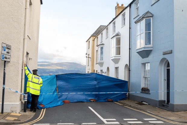 Police officer securing a crime scene with blue tarp.