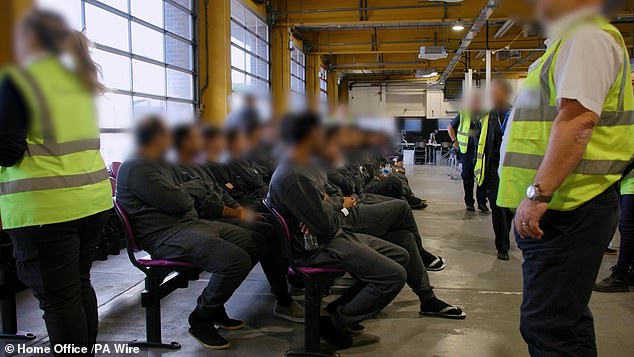 Waiting to be processed, migrants in grey sweatshirts sit in rows at a Home Office centre in Manston, Kent, yesterday