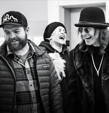Black and white photo of Jack Osbourne, his sister, and a friend laughing.