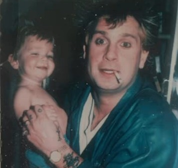 Photo of a young Jack Osbourne being held by Ozzy Osbourne.
