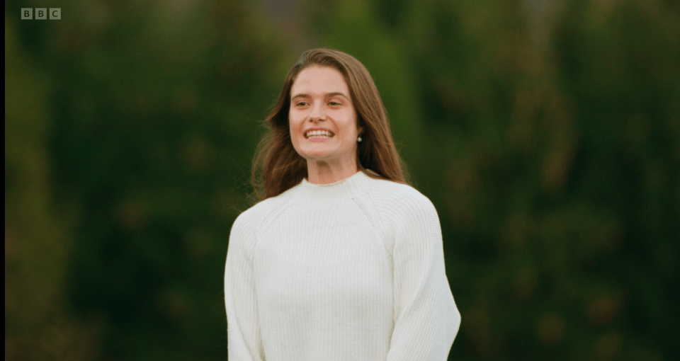 Smiling woman in white sweater.