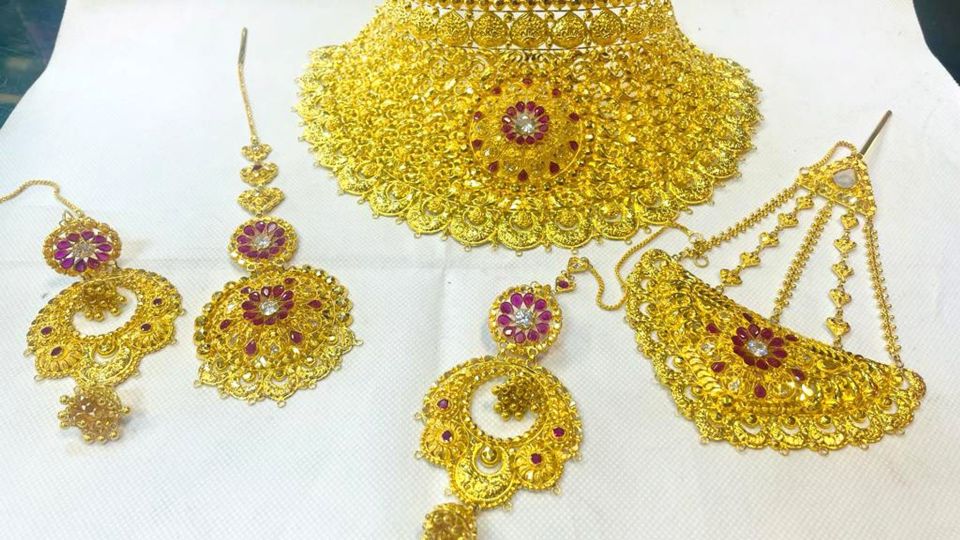 Gold necklace set with earrings and maang tikka.
