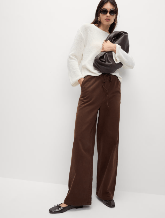 Woman wearing brown drawstring trousers and cream sweater.
