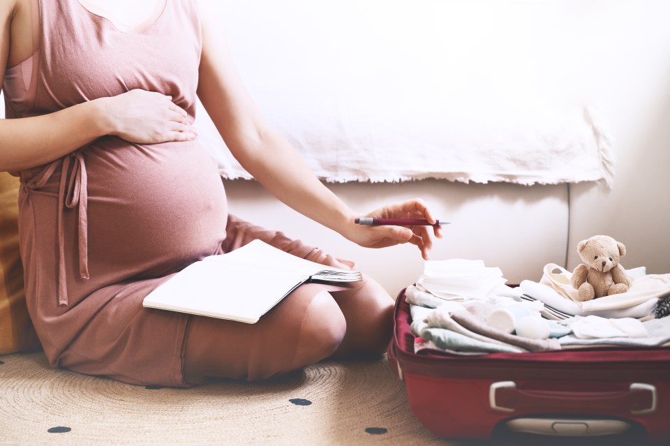 Pregnant woman packing a suitcase for the hospital.