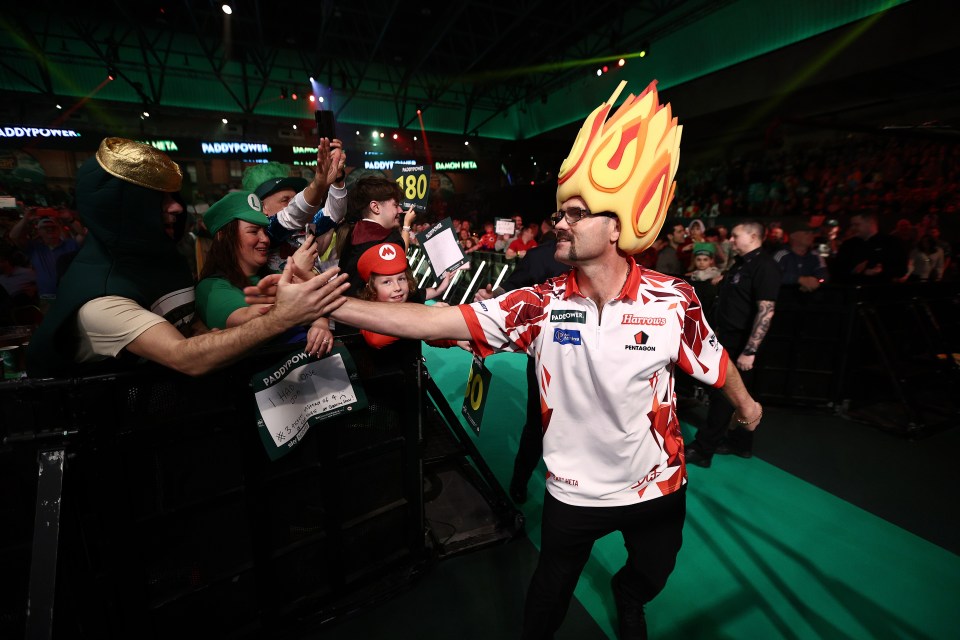 Damon Heta of Australia high-fiving fans before a darts match.