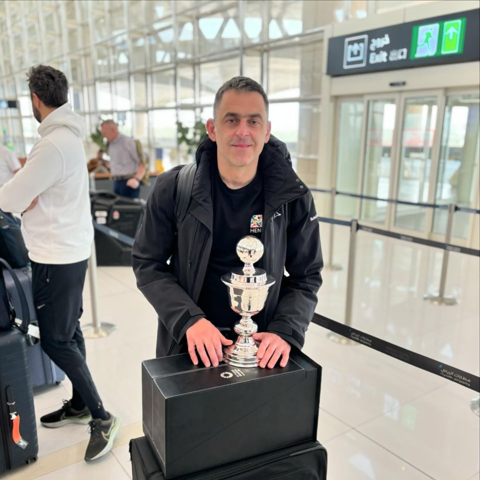 Ronnie O'Sullivan at an airport, holding a trophy.