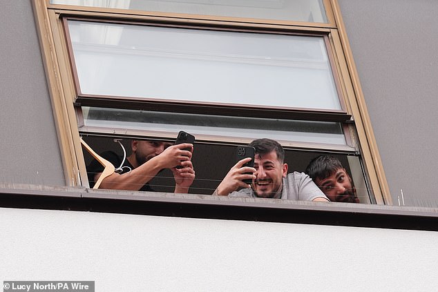 People believed to be migrants were seen filming and laughing from a window at the Thistle City Barbican Hotel in London