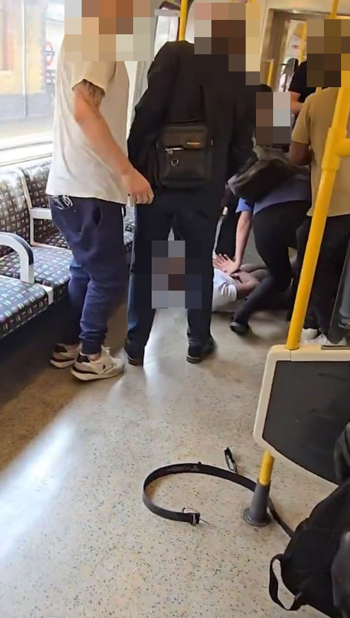 A man is being restrained on a subway car floor by several passengers.