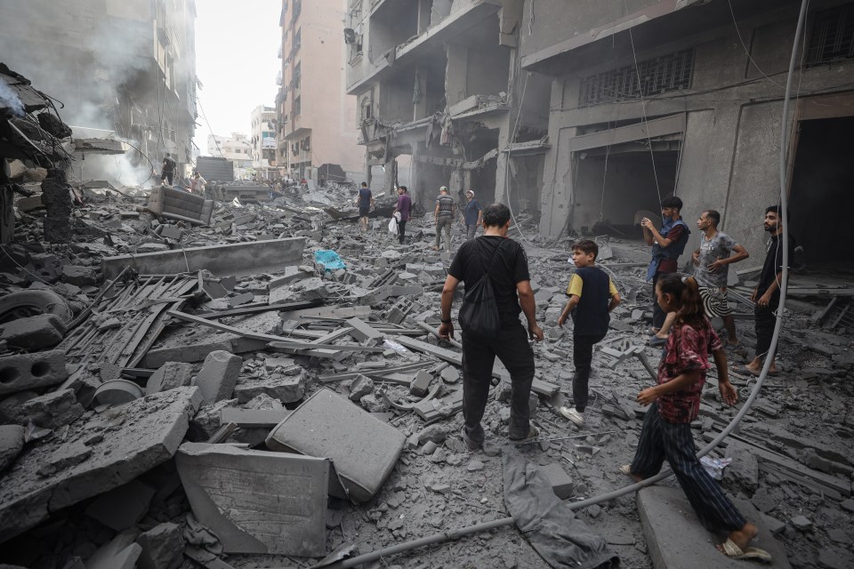 Aftermath of an Israeli airstrike in Gaza City, showing damaged buildings and civilians amidst the rubble.