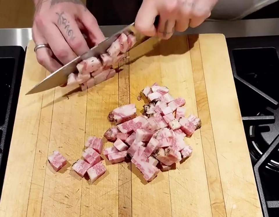 Person dicing meat on a wooden cutting board.