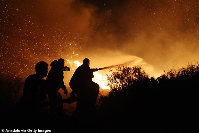 People attempt to battle a raging wildfire as flames and embers light up the night sky near the town of Keratea, southeast of Athens, Greece on August 08, 2025