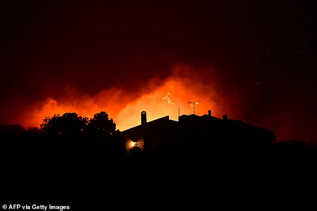 Flames engulf the fields and woods near a home as a wildfire rages near Palaia Fokaia, some 45 Km south of Athens, on August 8