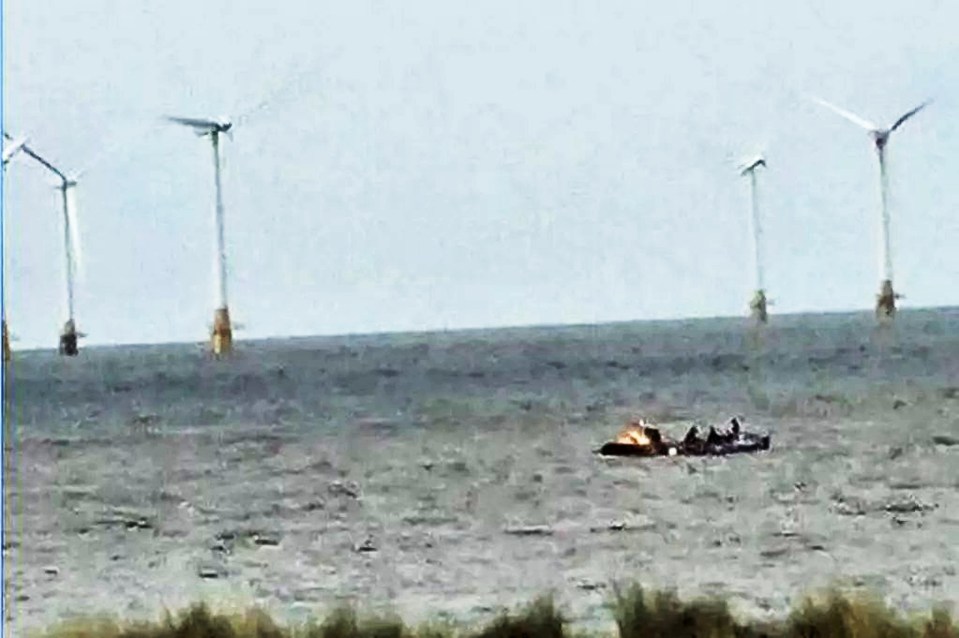 Photo of a small boat on the water near offshore wind turbines.