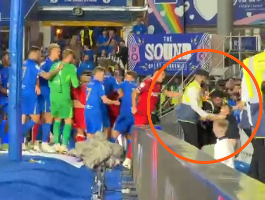 Soccer players celebrating near fans and security.