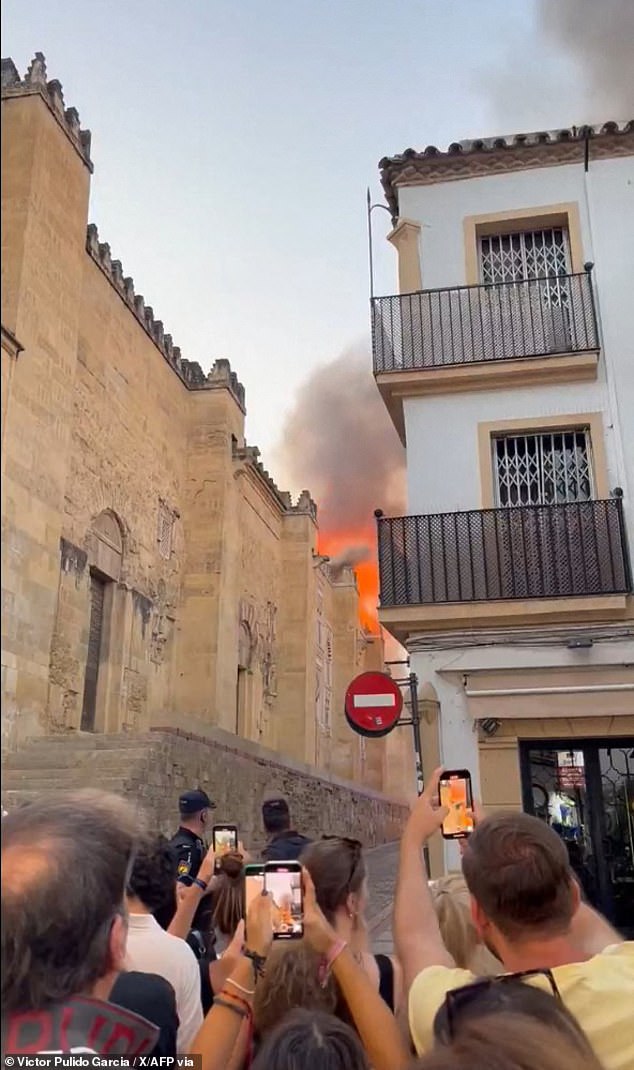 People using their mobile phone to capture images of the flames after a fire broke out in the historic mosque-turned-cathedral in the southern Spanish city of Cordoba