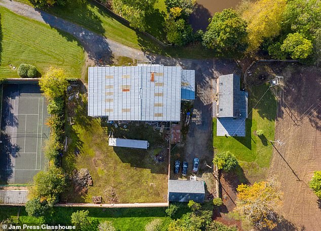 An overview of the property shows a tennis court to its side, with the house towering over the nearby trees
