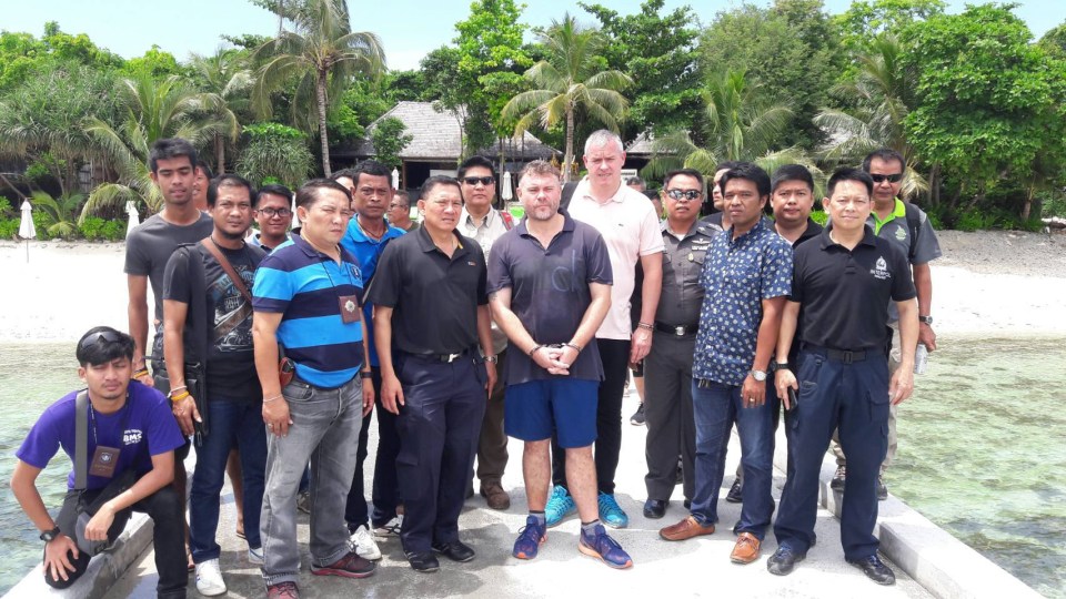 A British drug baron arrested in Thailand surrounded by police officers.
