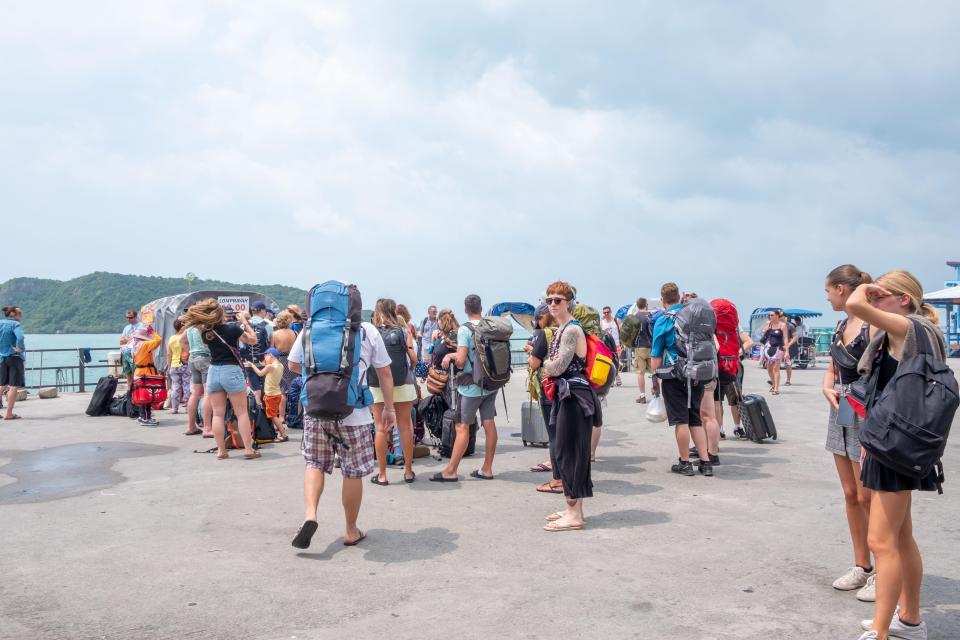 Passengers with backpacks waiting at a ferry terminal.