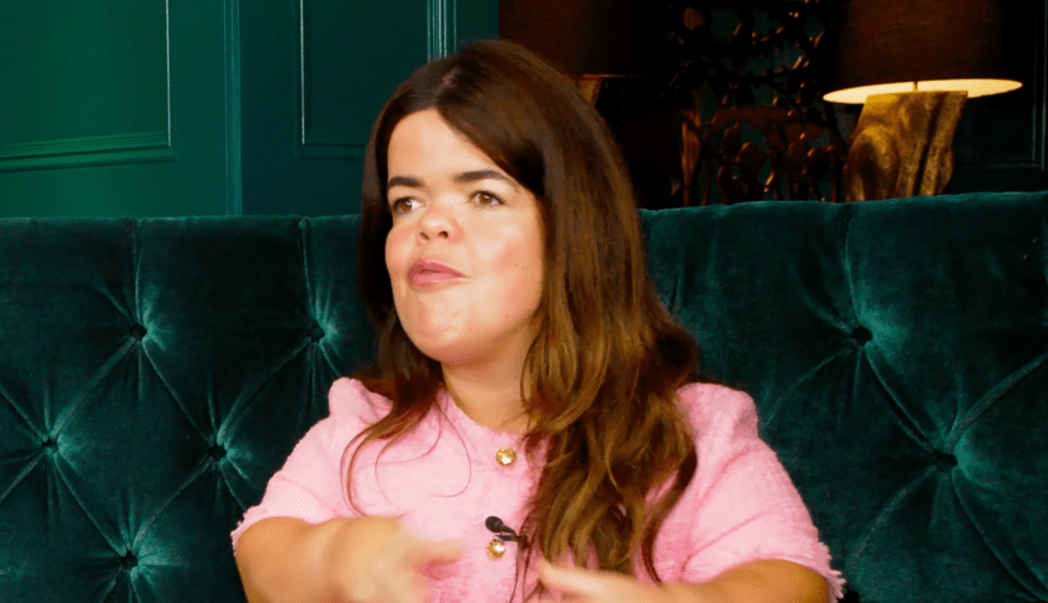 Hayley Meryl in a pink sweater, speaking.