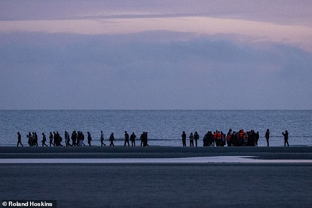 The images from today show the passengers gathering on the sand (pictured) as they wait to be loaded on to a boat at sunrise