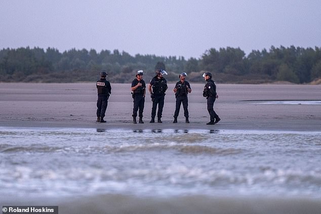 A handful of French police officers stood on the beach, watching on (pictured)