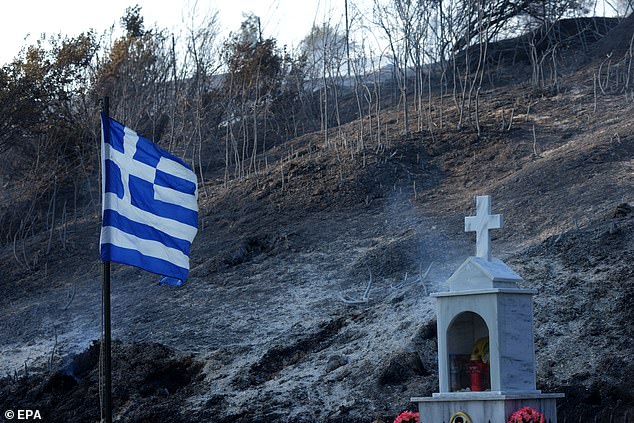 Greek flag is placed on a burned land after a wildfire that broke out in the area of Ancient Olympia, Peloponnese, Greece, 09 August 2025