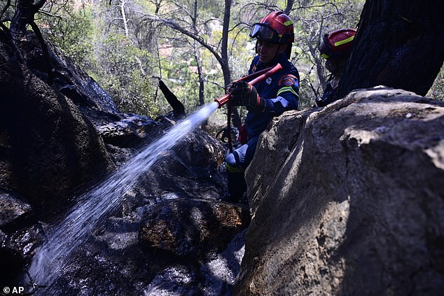 Two firefighters of the Wildfire Special Operation Unit, operate after a wildfire in Charvalo village, southeast of Athens, Greece, Saturday, Aug. 9, 2025