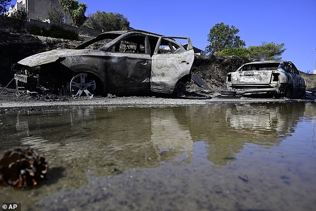 Burned cars reflect on water after a wildfire in Charvalo village, southeast of Athens, Greece, Saturday, Aug. 9, 2025